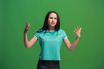 Image showing Beautiful female half-length portrait isolated on green studio backgroud. The young emotional surprised woman