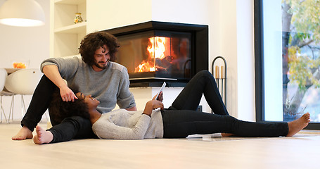 Image showing multiethnic couple using tablet computer on the floor