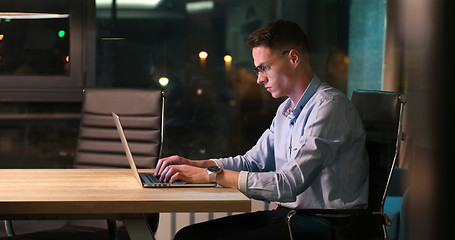 Image showing man working on laptop in dark office