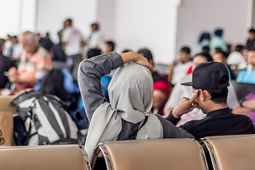 Image showing Modern muslim islamic asian couple sitting and waiting for flight departure at international airport terminal