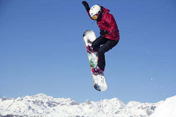 Image showing Snowboarder jumping through air with blue sky in background