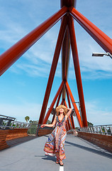 Image showing Female in long dress of vibrant patterns walking across Yandhai Nepean Crossing bridge