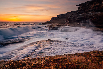 Image showing Sunrise and ocean cascades along coastal rocks and headland