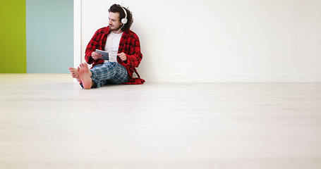 Image showing young man listenig music on tablet at home