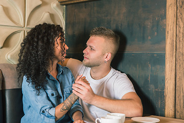 Image showing Happy young couple is drinking coffee and smiling while sitting at the cafe