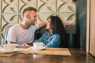 Image showing Happy young couple is drinking coffee and smiling while sitting at the cafe