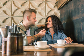 Image showing Happy young couple is drinking coffee and smiling while sitting at the cafe