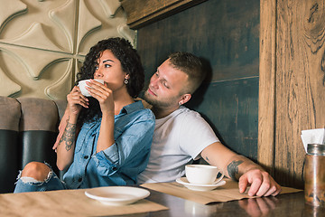 Image showing Happy young couple is drinking coffee and smiling while sitting at the cafe