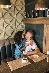 Image showing Happy young couple is drinking coffee and smiling while sitting at the cafe