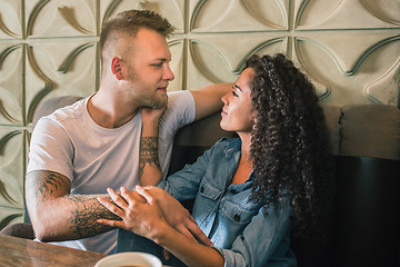 Image showing Happy young couple is drinking coffee and smiling while sitting at the cafe