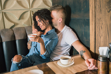 Image showing Happy young couple is drinking coffee and smiling while sitting at the cafe