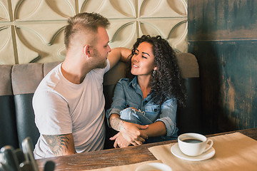 Image showing Happy young couple is drinking coffee and smiling while sitting at the cafe