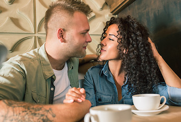 Image showing Happy young couple is drinking coffee and smiling while sitting at the cafe