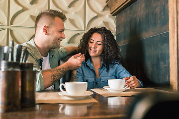 Image showing Happy young couple is drinking coffee and smiling while sitting at the cafe