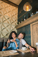 Image showing Happy young couple is drinking coffee and smiling while sitting at the cafe