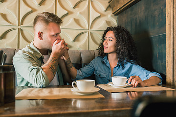 Image showing Happy young couple is drinking coffee and smiling while sitting at the cafe