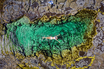 Image showing Carefree woman in bikini floating in beautiful rock pool summer 