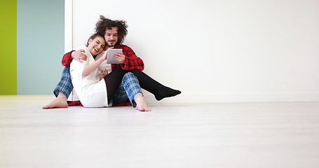 Image showing Young Couple using digital tablet on the floor