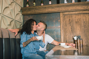 Image showing Happy young couple is drinking coffee and smiling while sitting at the cafe