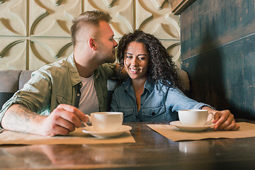 Image showing Happy young couple is drinking coffee and smiling while sitting at the cafe