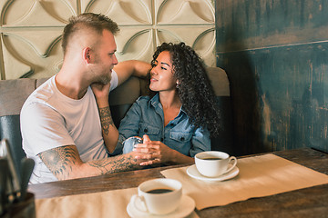 Image showing Happy young couple is drinking coffee and smiling while sitting at the cafe