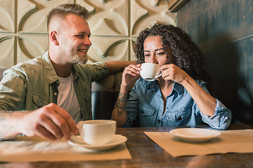 Image showing Happy young couple is drinking coffee and smiling while sitting at the cafe