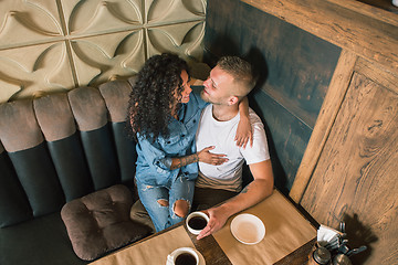 Image showing Happy young couple is drinking coffee and smiling while sitting at the cafe