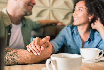 Image showing Happy young couple is drinking coffee and smiling while sitting at the cafe