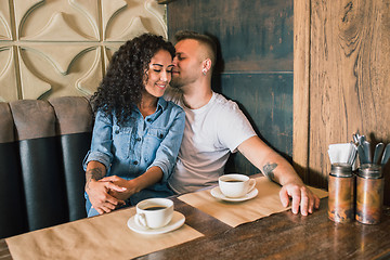 Image showing Happy young couple is drinking coffee and smiling while sitting at the cafe