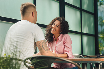 Image showing Close up on a man and a woman holding hands at a wooden table