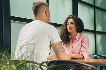 Image showing Close up on a man and a woman holding hands at a wooden table