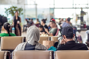 Image showing Modern muslim islamic asian couple sitting and waiting for flight departure at international airport terminal