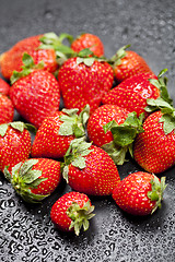 Image showing Fresh ripe strawberry with water drops on black.