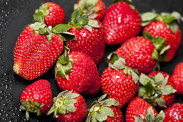 Image showing Fresh ripe strawberry with water drops on black