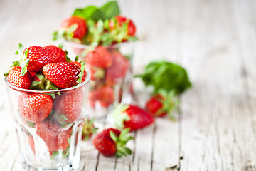 Image showing Organic red strawberries in two glasses and mint leaves on rusti