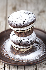 Image showing Chocolate dark muffins with sugar powder on brown plate on rusti