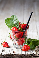 Image showing Organic red strawberries glass and mint leaves on rustic wooden 