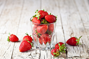 Image showing Organic red strawberries in glass on rustic wooden background. 