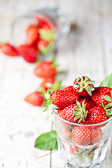 Image showing Organic red strawberries in two glasses and mint leaves on rusti