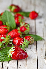 Image showing Fresh red strawberries and mint leaves on rustic wooden backgrou