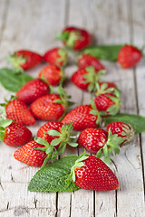 Image showing Fresh red strawberries and mint leaves on rustic wooden backgrou