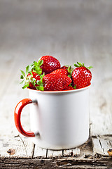 Image showing Organic red strawberries in white ceramic cup on rustic wooden b