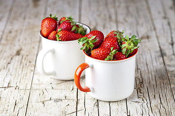 Image showing Organic red strawberries in two white ceramic cups on rustic woo