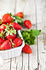 Image showing Fresh red strawberries in white bowl and mint leaves on rustic w