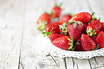 Image showing Organic red strawberries on white plate on rustic wooden backgro