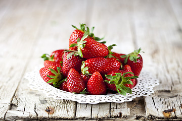 Image showing Organic red strawberries on white plate on rustic wooden backgro