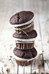 Image showing Chocolate dark muffins on rustic wooden table.