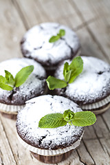 Image showing Chocolate dark muffins with sugar powder and mint leaf on rustic