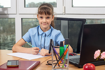 Image showing A girl of eight years old at the table in the office plays in the office employee