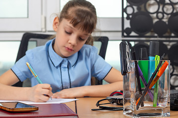 Image showing Eight years old girl working in the office, focusing on office supplies